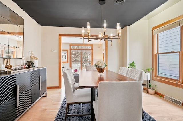 dining space featuring light hardwood / wood-style flooring and a chandelier