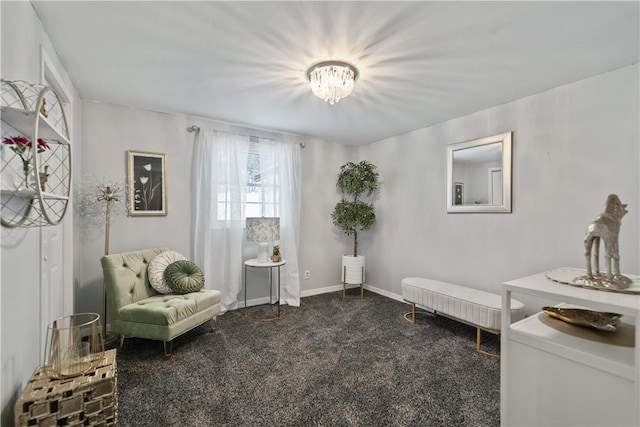 sitting room featuring dark colored carpet and a notable chandelier