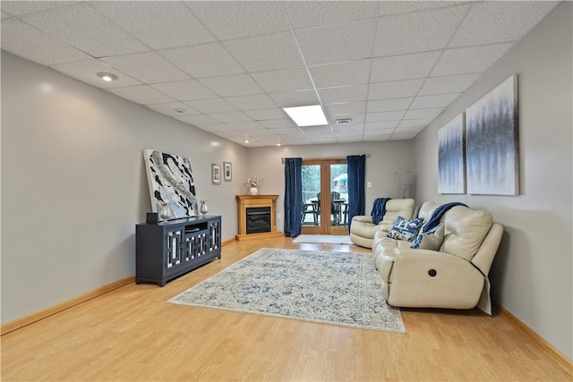 living room featuring wood-type flooring, a paneled ceiling, and french doors