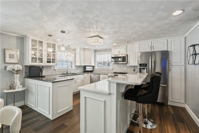 kitchen featuring pendant lighting, stainless steel appliances, white cabinetry, and dark wood-type flooring