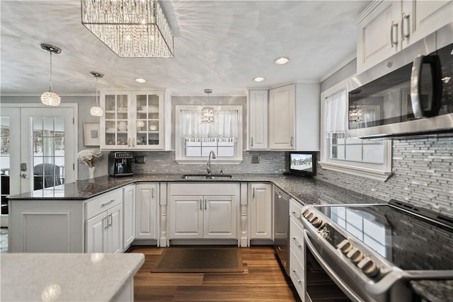 kitchen with stainless steel appliances, white cabinetry, hanging light fixtures, and sink