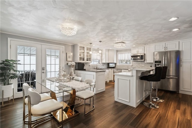 kitchen featuring white cabinets, appliances with stainless steel finishes, hanging light fixtures, and sink