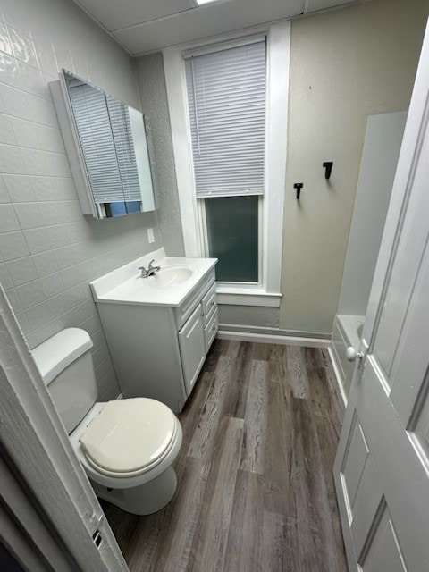 bathroom featuring hardwood / wood-style floors, vanity, toilet, and tile walls