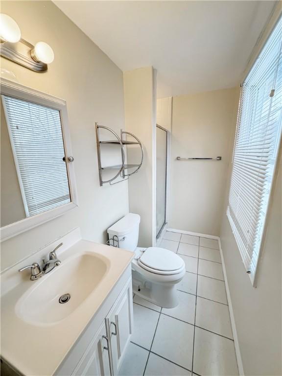 bathroom featuring tile patterned flooring, vanity, an enclosed shower, and toilet