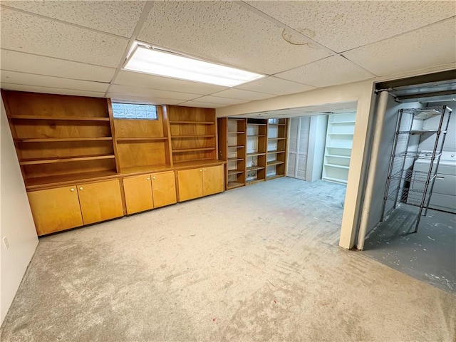 basement featuring light colored carpet, washer / clothes dryer, and a drop ceiling