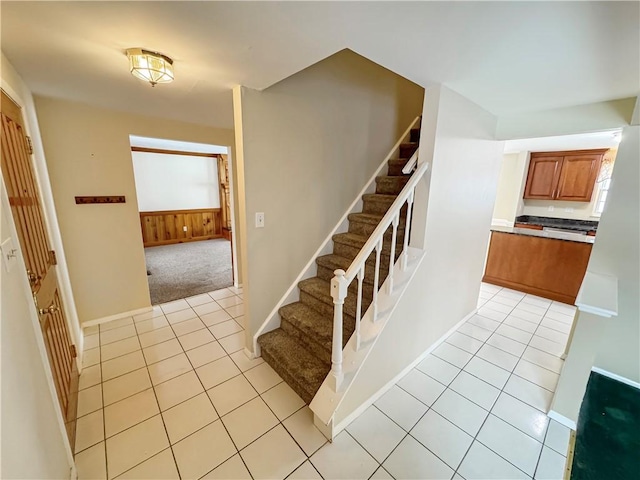 stairway with tile patterned floors and wooden walls