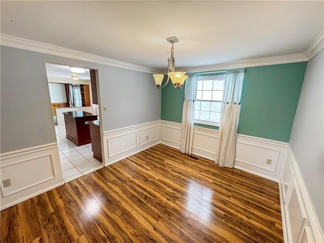 unfurnished dining area with ornamental molding, light hardwood / wood-style flooring, and a chandelier