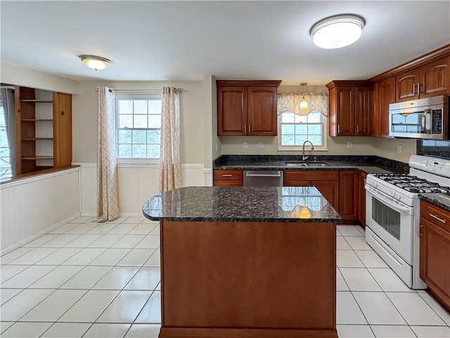 kitchen with sink, a center island, stainless steel appliances, dark stone countertops, and light tile patterned floors