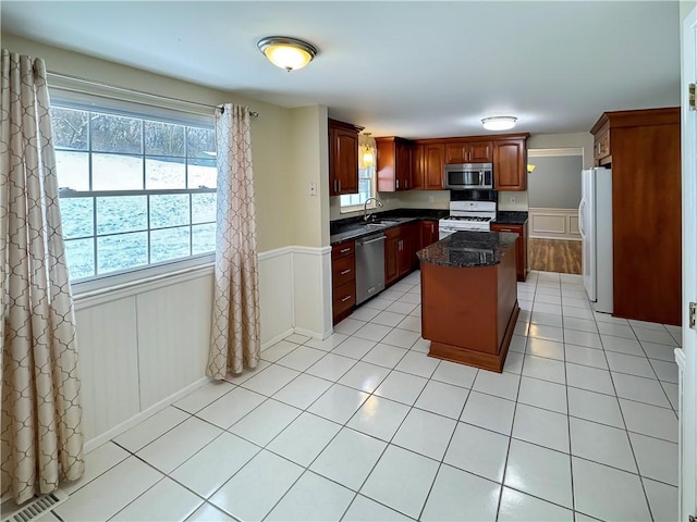 kitchen with a kitchen island, light tile patterned flooring, sink, and appliances with stainless steel finishes