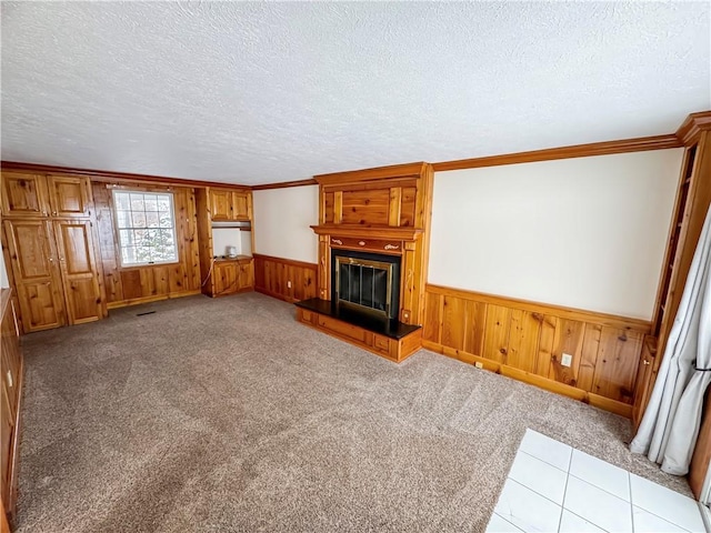 unfurnished living room with a fireplace, light carpet, a textured ceiling, and ornamental molding