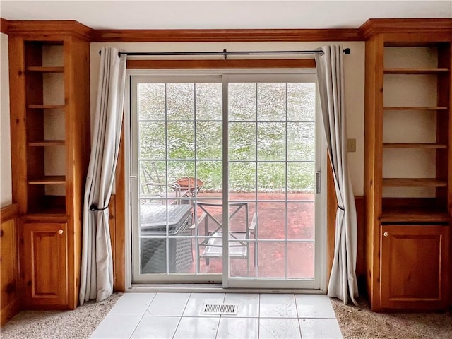 doorway featuring light tile patterned flooring and ornamental molding