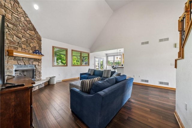 living room featuring dark hardwood / wood-style floors, a stone fireplace, and high vaulted ceiling