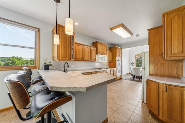 kitchen featuring pendant lighting, a breakfast bar, kitchen peninsula, and sink