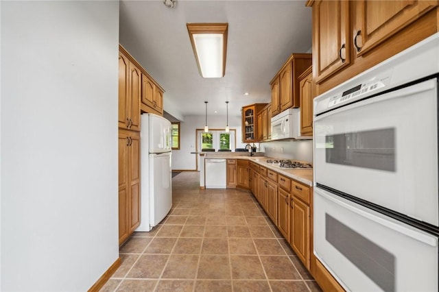 kitchen featuring white appliances, hanging light fixtures, and sink