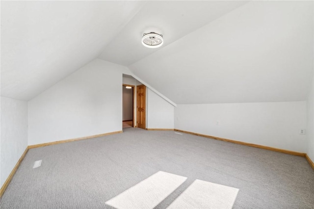 additional living space featuring light colored carpet and vaulted ceiling