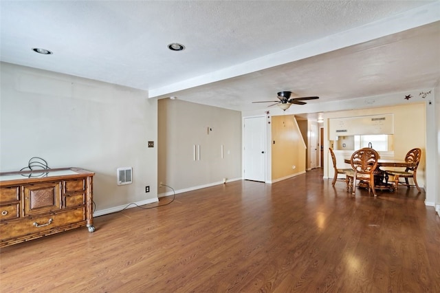 living room featuring ceiling fan, beam ceiling, wood-type flooring, and a textured ceiling