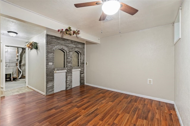 unfurnished living room with ceiling fan, dark wood-type flooring, and a textured ceiling