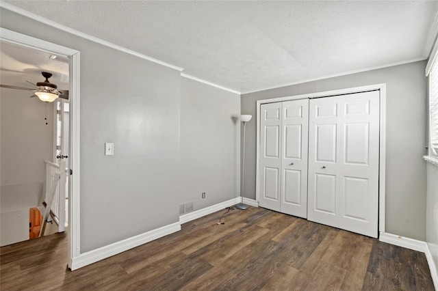 unfurnished bedroom featuring dark wood-type flooring, ceiling fan, ornamental molding, a textured ceiling, and a closet