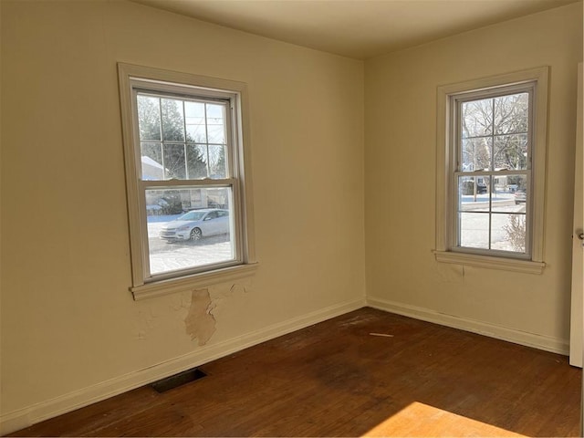 unfurnished room with dark wood-type flooring and a wealth of natural light