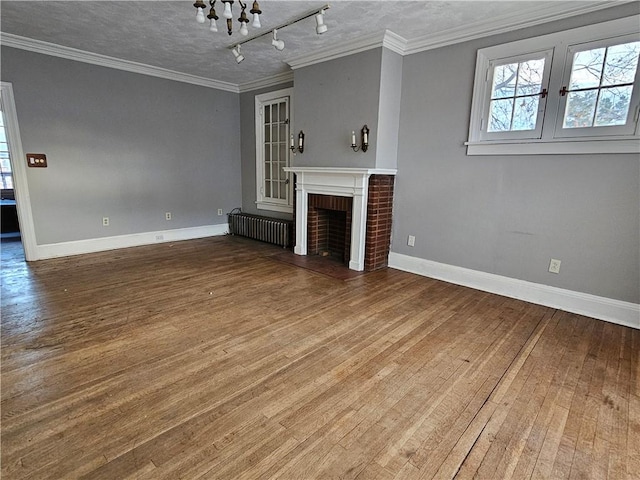 unfurnished living room featuring ornamental molding, a textured ceiling, radiator, and a brick fireplace