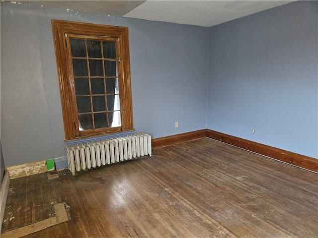 unfurnished room with wood-type flooring and radiator heating unit