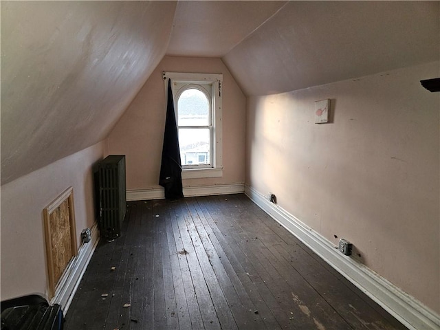 additional living space with radiator heating unit, dark hardwood / wood-style flooring, and vaulted ceiling