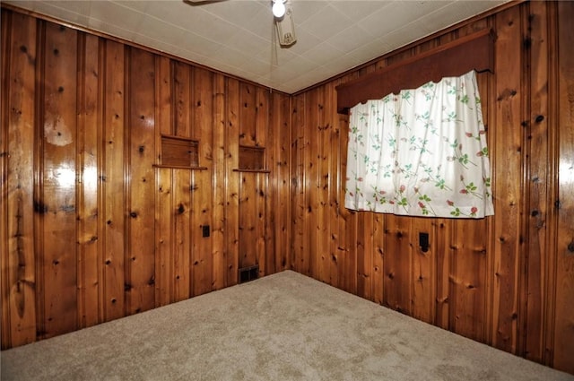 unfurnished room with carpet floors, ceiling fan, and wooden walls