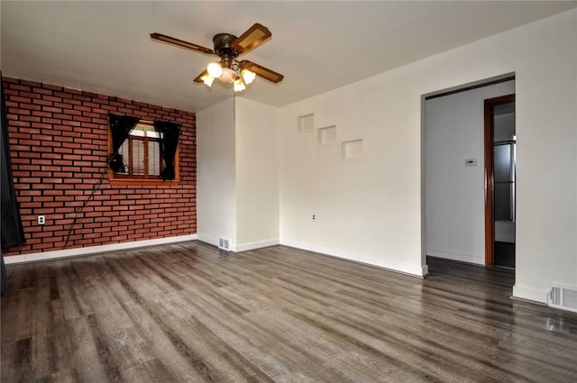 unfurnished room featuring ceiling fan, brick wall, and dark hardwood / wood-style floors