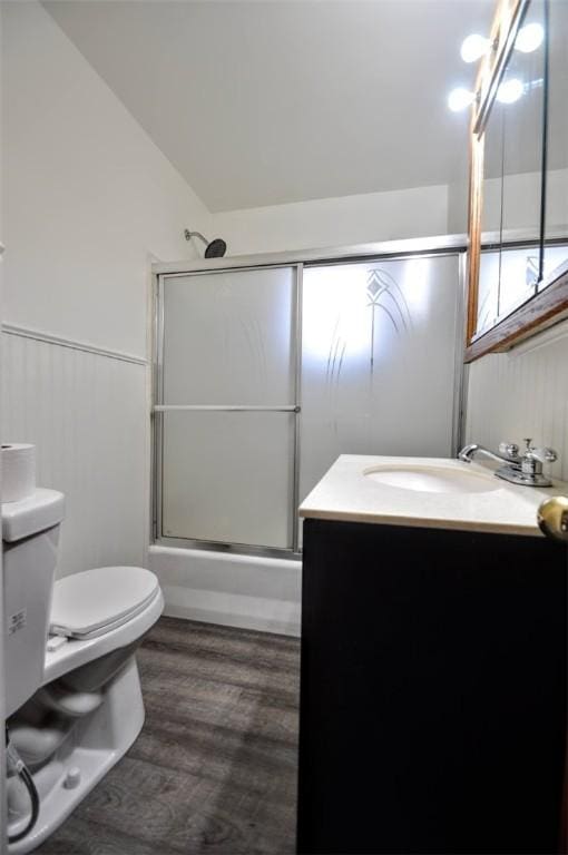 full bathroom with bath / shower combo with glass door, vanity, wood-type flooring, toilet, and lofted ceiling