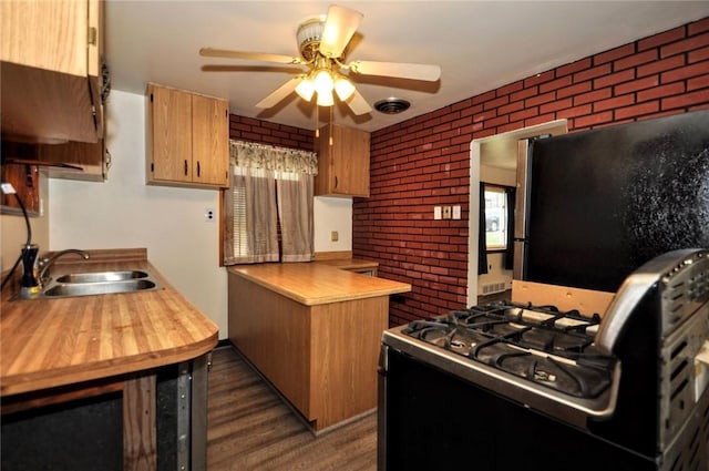 kitchen with stainless steel fridge, brick wall, ceiling fan, sink, and black gas stove