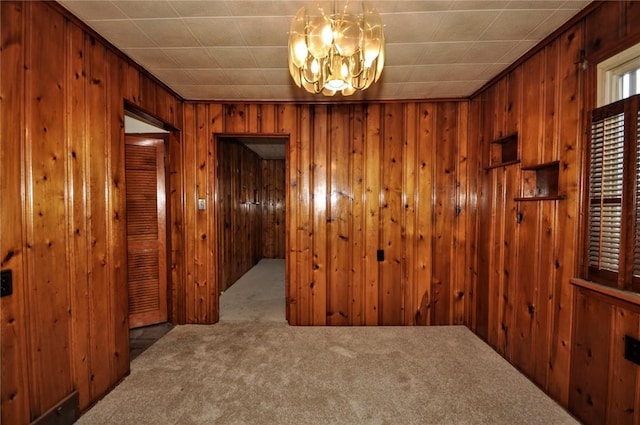 empty room with carpet flooring, a chandelier, and wooden walls