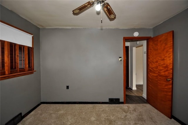 empty room with ceiling fan and dark colored carpet