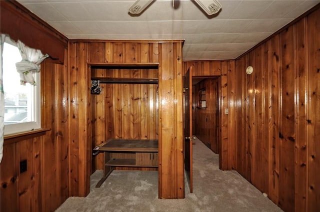 interior space with carpet, ceiling fan, and wooden walls