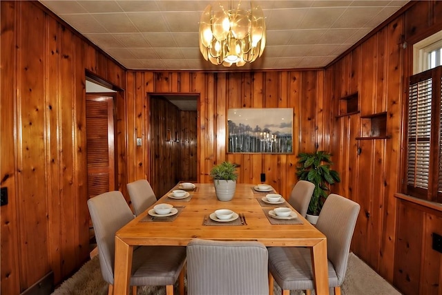 carpeted dining room with a notable chandelier and wooden walls