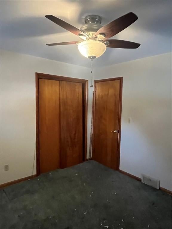 unfurnished bedroom with dark colored carpet and ceiling fan