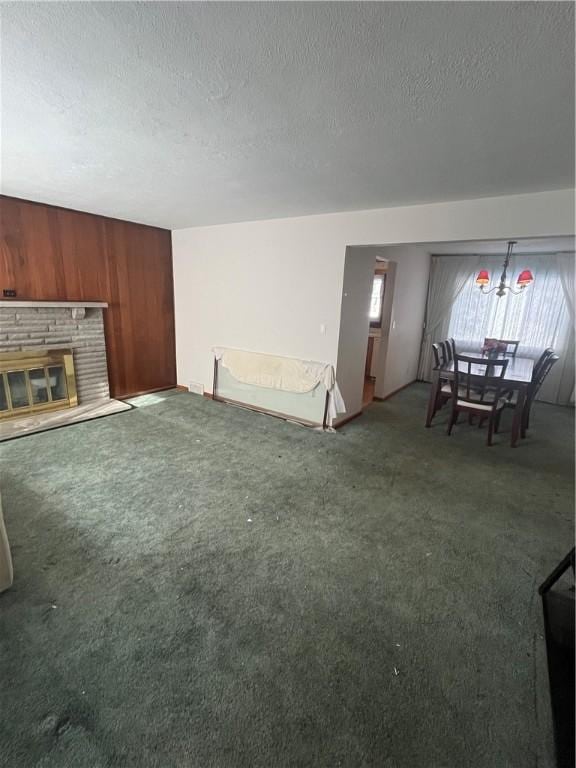 unfurnished living room featuring a fireplace, wood walls, a textured ceiling, and dark carpet