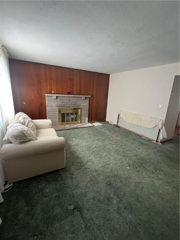 living room with dark colored carpet, a textured ceiling, wooden walls, and a brick fireplace