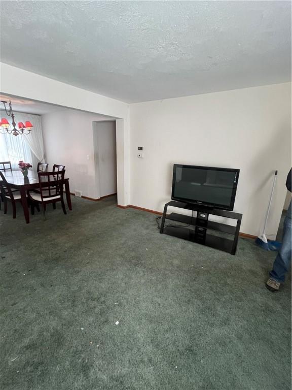 carpeted living room featuring a textured ceiling and a chandelier