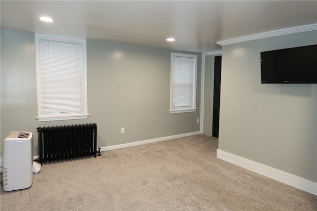 basement featuring light colored carpet, radiator, and ornamental molding