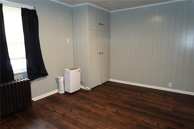 empty room featuring radiator, crown molding, and dark hardwood / wood-style flooring