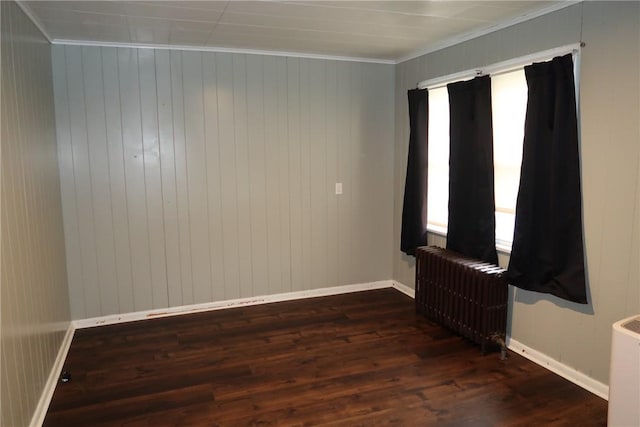 unfurnished room with crown molding, radiator, dark wood-type flooring, and wood walls