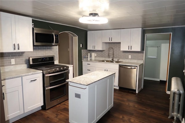 kitchen with a center island, sink, dark wood-type flooring, white cabinets, and appliances with stainless steel finishes