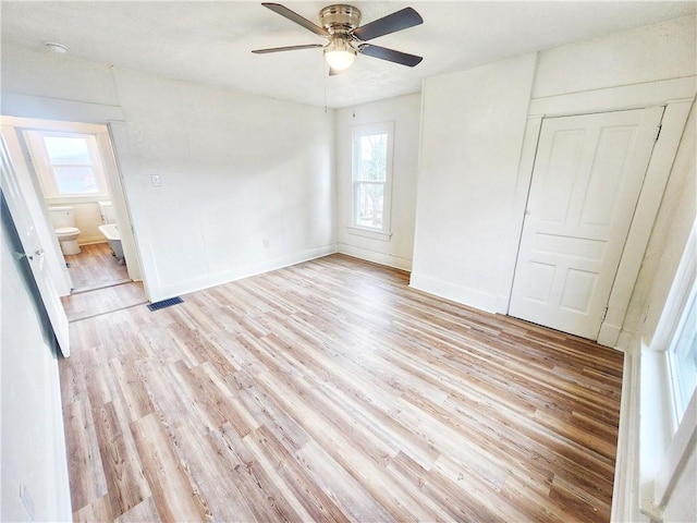 unfurnished bedroom with a closet, light wood-type flooring, ensuite bathroom, and ceiling fan