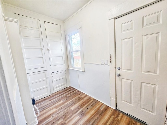 interior space with light hardwood / wood-style floors, ornamental molding, and a closet