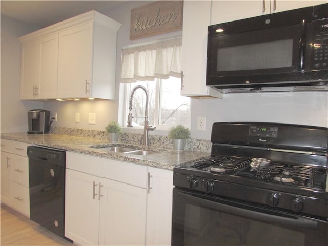 kitchen featuring sink, light stone counters, white cabinetry, and black appliances