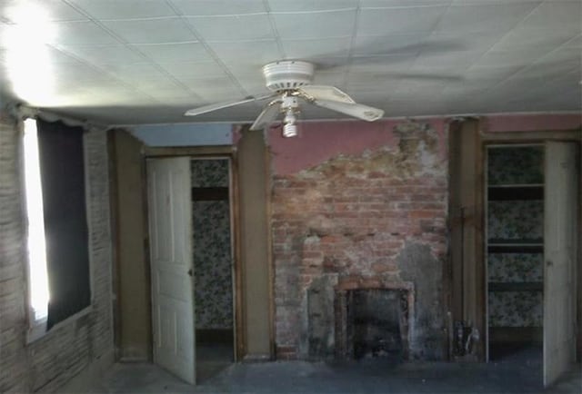 unfurnished living room with ceiling fan and a fireplace