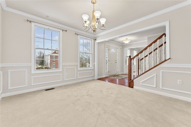 entrance foyer featuring crown molding, carpet floors, and a chandelier