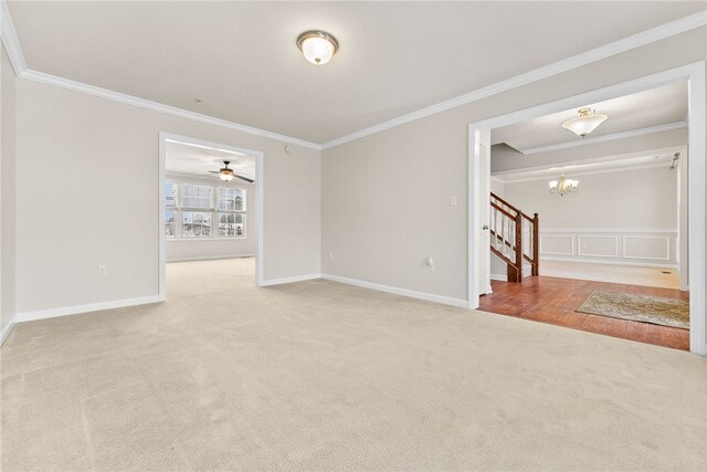 unfurnished room featuring ceiling fan with notable chandelier, light colored carpet, and ornamental molding