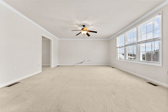 empty room with ceiling fan, light colored carpet, and ornamental molding