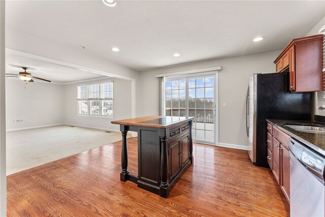 kitchen with ceiling fan, sink, hardwood / wood-style floors, a kitchen island, and appliances with stainless steel finishes